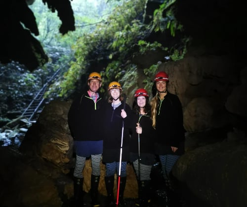 Group photo at the cave entrance wearing helmets before a Down to Earth Glowworm Cave Tour in Waitomo.